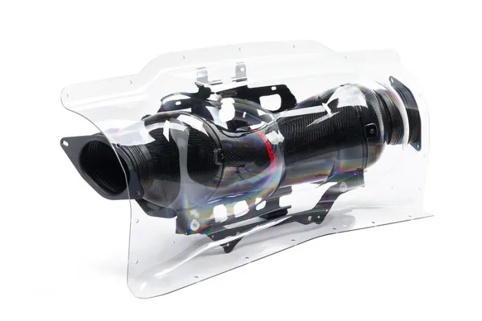 A carbon fiber automotive air intake system encased in a clear, contoured plastic cover, positioned against a plain white background for display.