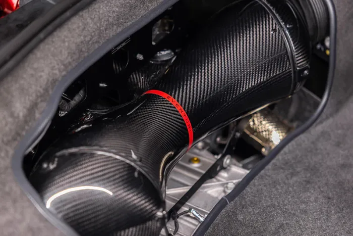 A black carbon fiber intake pipe with red lettering "EVENTURI" sits within an engine bay, surrounded by dark, fabric-lined components and metallic elements.