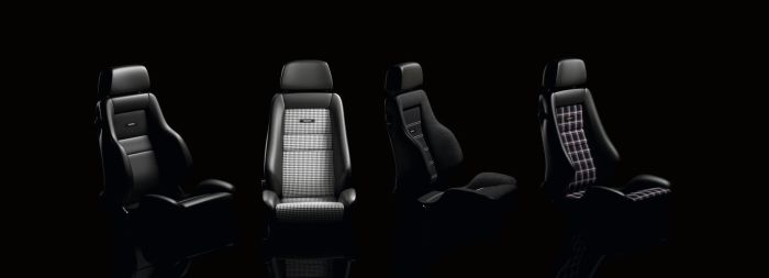 Four car seats are aligned in a row against a black background, showcasing different upholstery designs, including plain leather, checkered fabric, and cloth. Labels reading "RECARO" are visible on two seats.