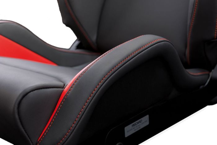 Racing car seat with grey and red upholstery, detailed with red stitching, positioned in a vehicle interior. Plaque at the base of the seat reads, "RECARO."