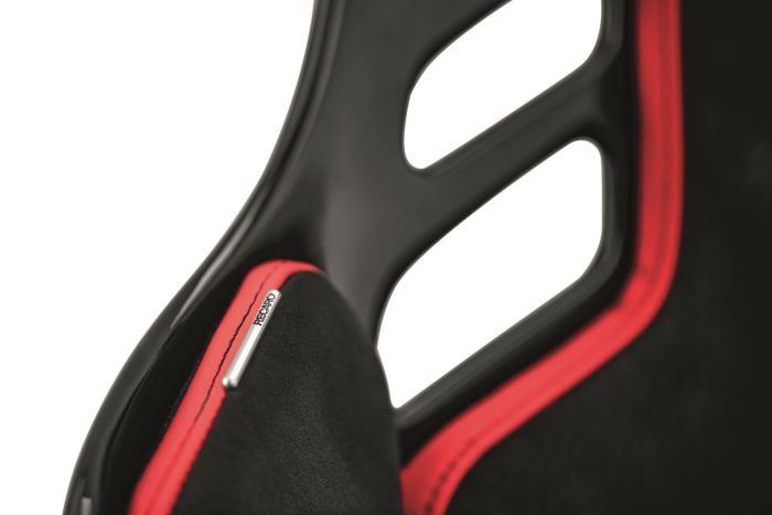 A black and red racing-style seat with "RECARO" text on a metal label features a sleek design and cutout elements, highlighting its sporty and ergonomic attributes.