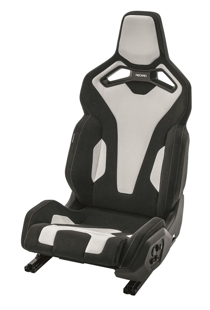 A black and white racing car seat is shown in a studio setting. The seat features ergonomic padding, integrated headrest, and the brand name "RECARO" written on the headrest area.