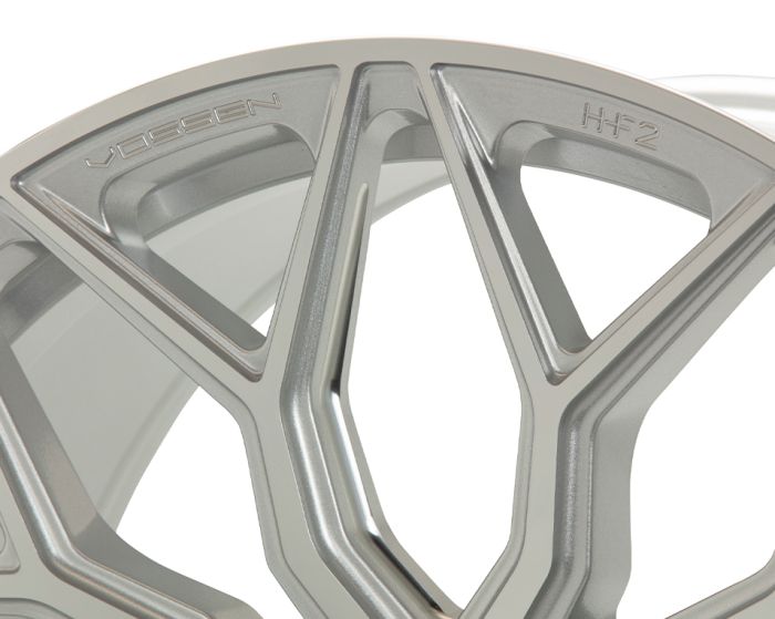 A metallic car wheel rim with intricate, angular patterns, labeled "Vossen" and "HF-2," displayed against a plain white background.