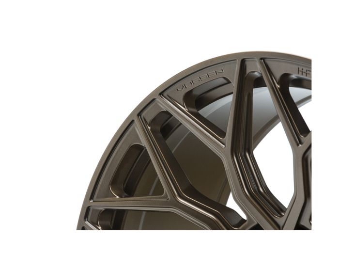 Intricately designed metallic wheel rim displaying detailed geometric patterns, set against a plain background. Text reads “Vossen” and “HFS6.”