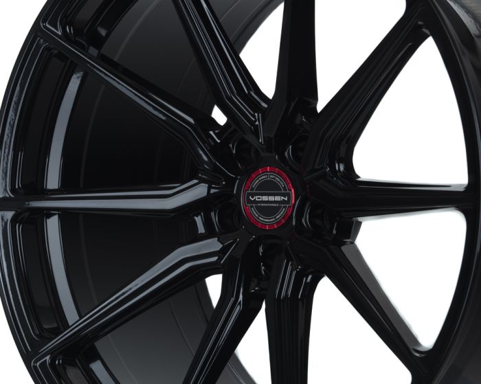 Shiny black alloy wheel with six split spokes, featuring a central hubcap displaying "VOSSEN" text; set against a plain white background.