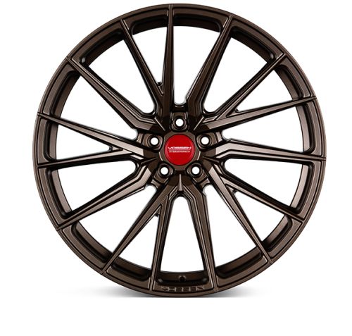 A bronze car wheel rim with multiple thin spokes radiates outward. The center displays a red circle with the text "VOSSEN FORGED." The rim is set against a plain white background.