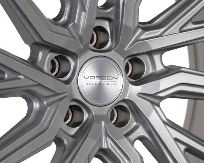 A metallic alloy wheel with a star-shaped design displays the text "VOSSEN HYBRID FORGED" on its center cap, set against a neutral background.