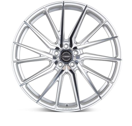 A silver, multi-spoke alloy wheel features intricate design patterns. Text on the center cap reads: "VOSSEN FORGED" with "VOSSEN" at the bottom of the wheel. Plain background.