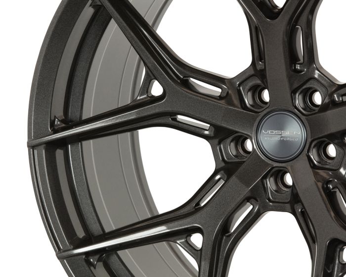 A metallic car wheel rim with intricate spoke design; "VOSSEN HYBRID FORGED" is inscribed on the center cap, set against a plain white background.