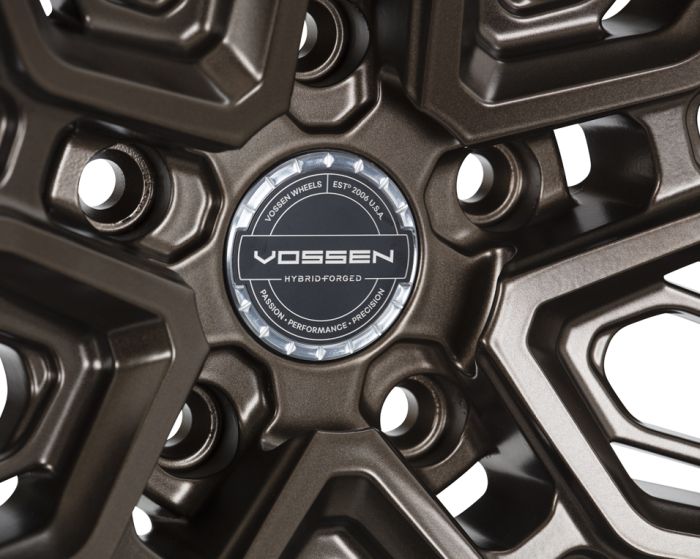 Bronze alloy wheel features five spokes with a polished center cap labeled “VOSSEN, HYBRID FORGED.” Surrounding text: “VOSSEN WHEELS EST. 2006 U.S.A PASSION • PERFORMANCE • PRECISION.”