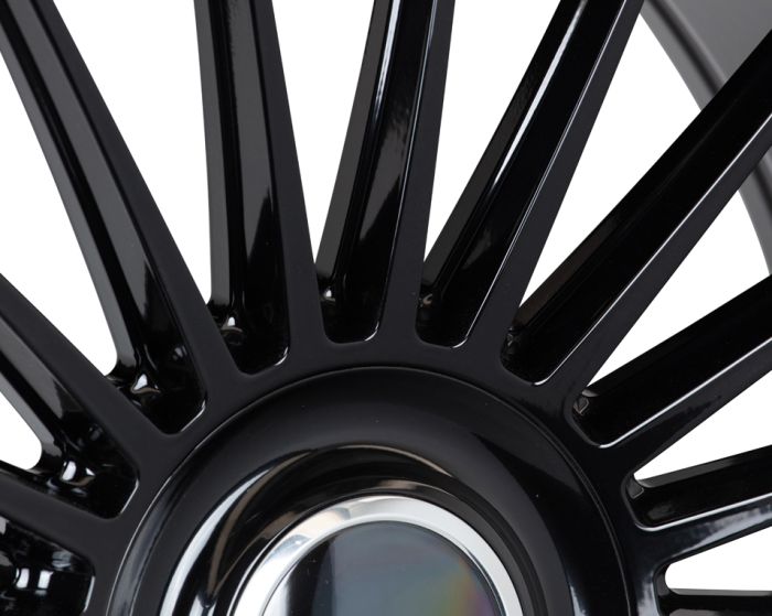 Black metal wheel spokes radiate symmetrically from a shiny central hub, reflecting light in a sleek, industrial setting. No text is present.