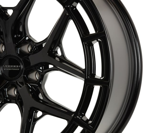 A glossy black alloy wheel with intricate spoke design, featuring the text "Vossen Hybrid Forged" at the center, displayed against a plain white background.