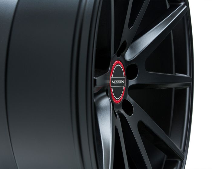 A black alloy wheel with a red-accented center cap features the text "VOSSEN" in white. It is showcased against a clean, white background.