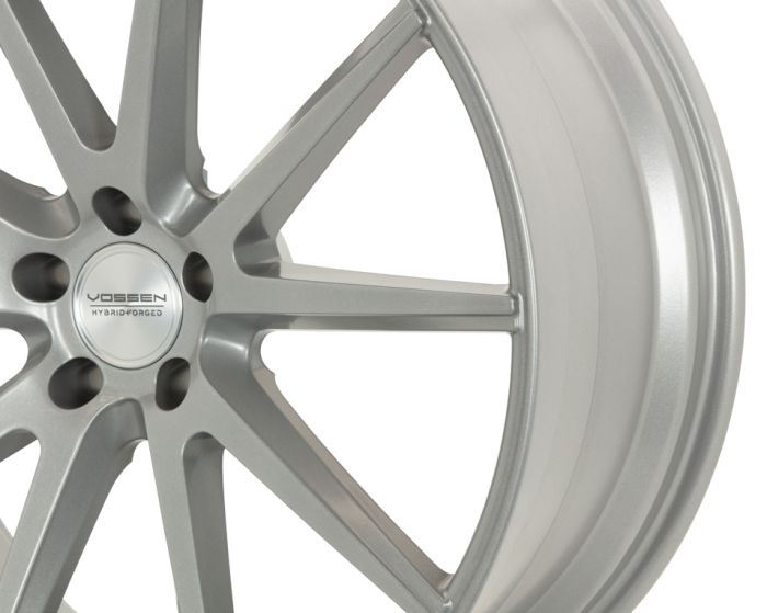 A silver alloy car wheel with multi-spoke design, displaying the text "VOSSEN HYBRID FORGED" at the center, against a plain white background.