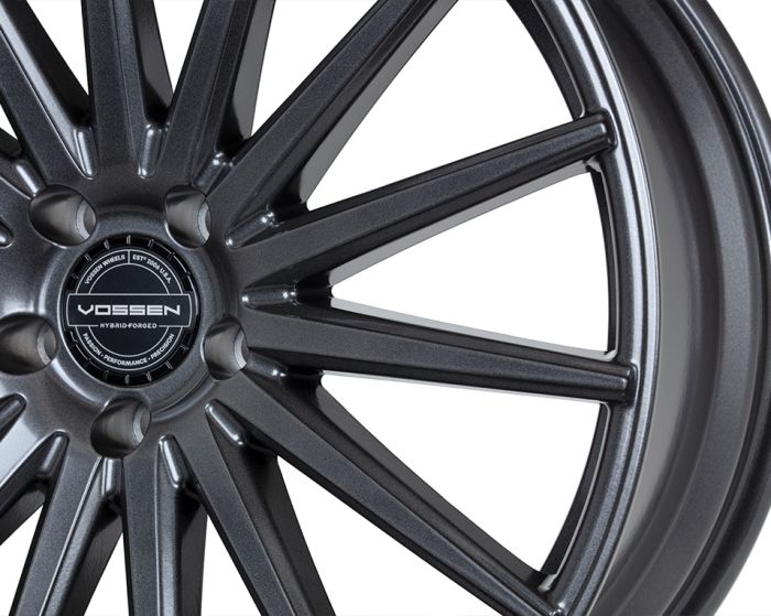 A metallic wheel rim displays a sleek, multi-spoke design against a plain background. Text reads: "VOSSEN HYBRID-FORGED," "VOSSEN WHEELS EST. 2006 U.S.A.," and "PASSION-PERFORMANCE-PRECISION."