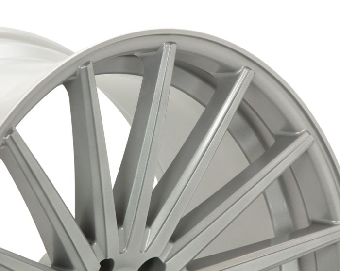 A silver alloy wheel with multiple spokes is angled, highlighting its glossy, smooth surface. The background is a neutral, light color, emphasizing the wheel's design and texture.